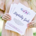 The Hospitality Guide being held by Brettnay Brazzell. They are slightly flayed out so that you can see it is multiple pages. She is wearing a peach colored dress.