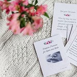 labor and delivery cards. It depicts the cards spread out on the white table cloth with the pink flowers beside them.