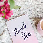 Head to Toe Prayer Journal. The pink edition of the book is laying on a white cloth with flowers and coffee nearby