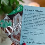 Two "Children of Character Cards" being held in a woman's hand with fingernails painted red. It shows the front and back of the cards to display their design. In the background is a plant on a table which is out of focus.