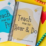 The Sermon Note Journal just barely on top of the Prayer Journal. Around them are bead bracelets and necklaces