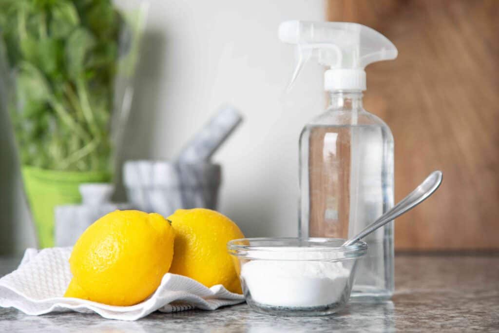 Fresh lemons with cleaning supplies and disinfectant spray for natural cleaning.