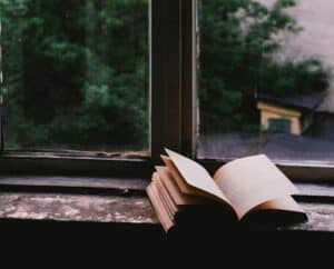 Open book on windowsill with natural view, symbolizing spiritual growth and calling.