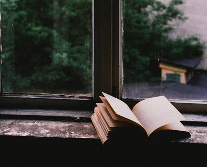 Open book on windowsill with natural view, symbolizing spiritual growth and calling.